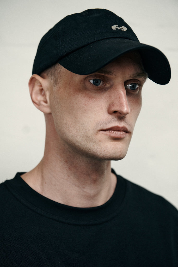 Man wearing a black SCEND CHROME LOGO CAP against a plain background