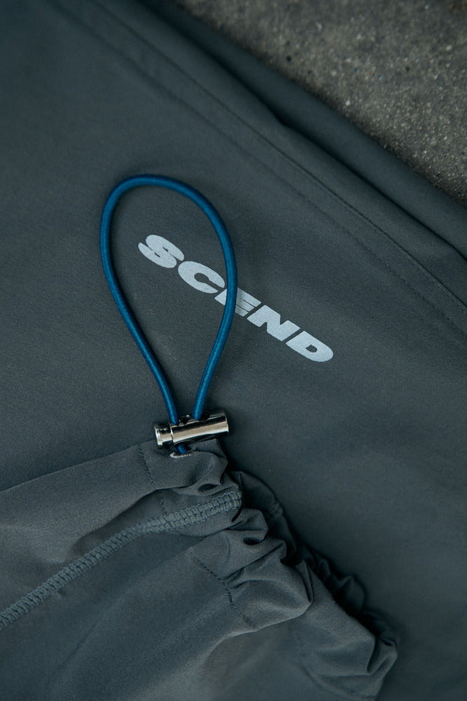 Close-up of a dark gray bag with a blue zipper and 'Scand' branding.