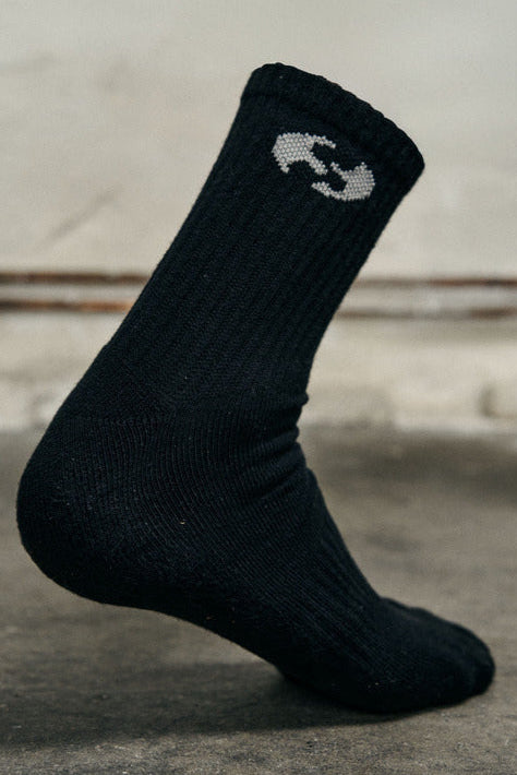 Black sock with a white logo on a concrete floor